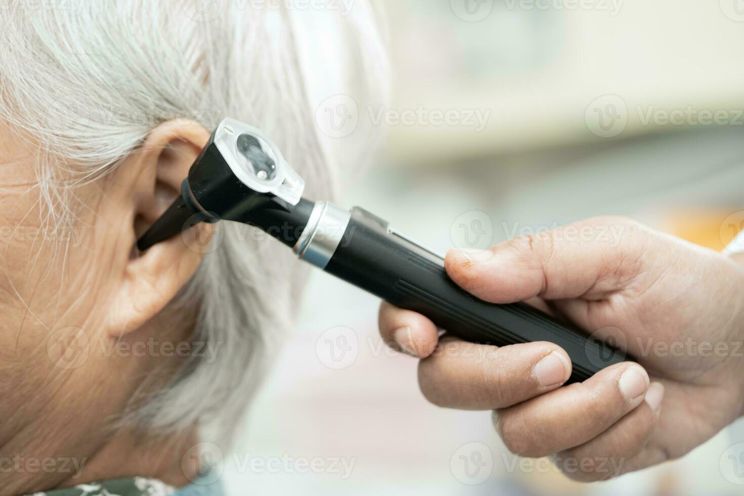 audiologiste ou ent médecin utilisation otoscope vérification oreille de asiatique Sénior femme patient traiter audition perte problème. photo