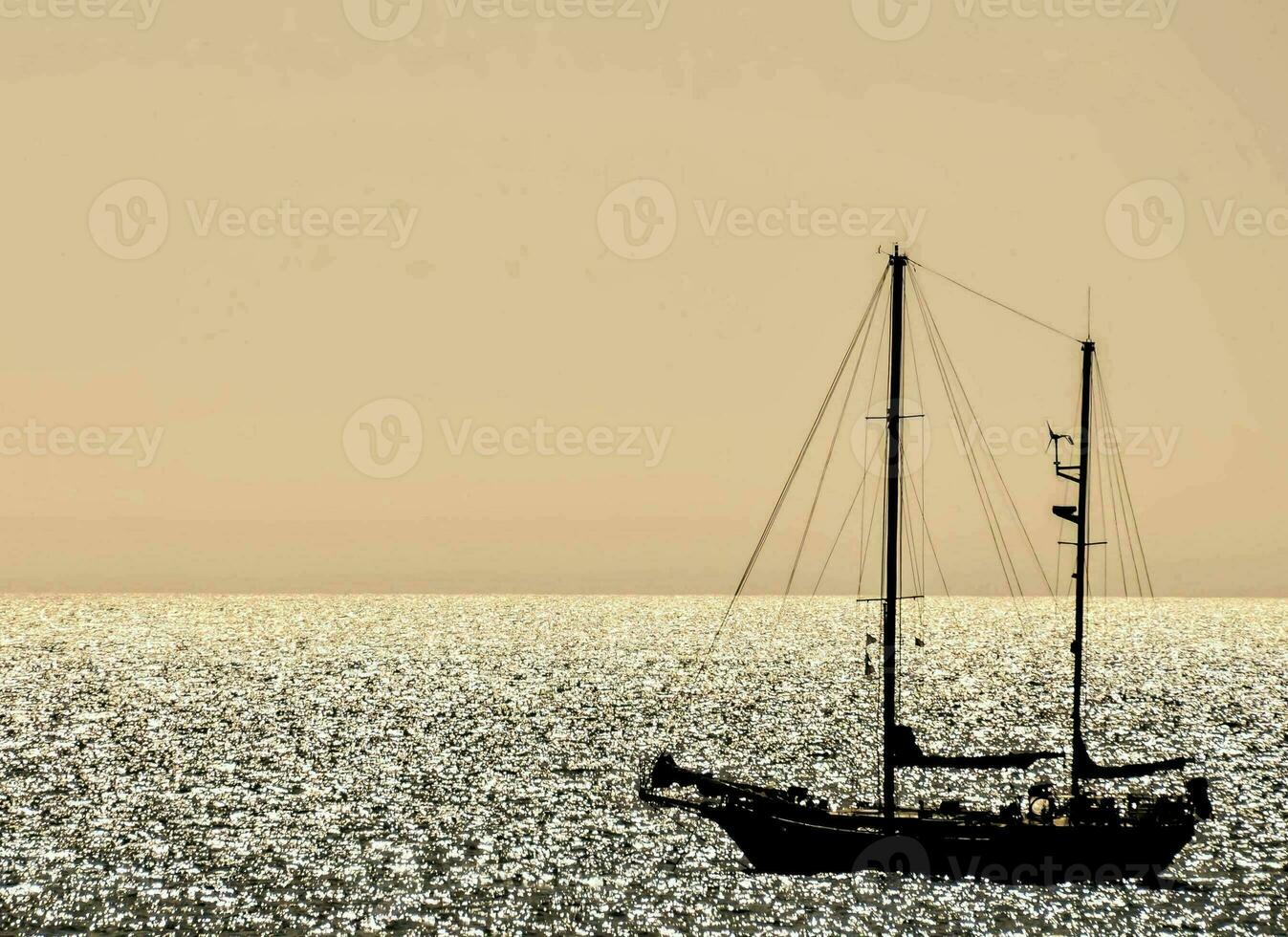 une voilier est vu dans le océan à le coucher du soleil photo