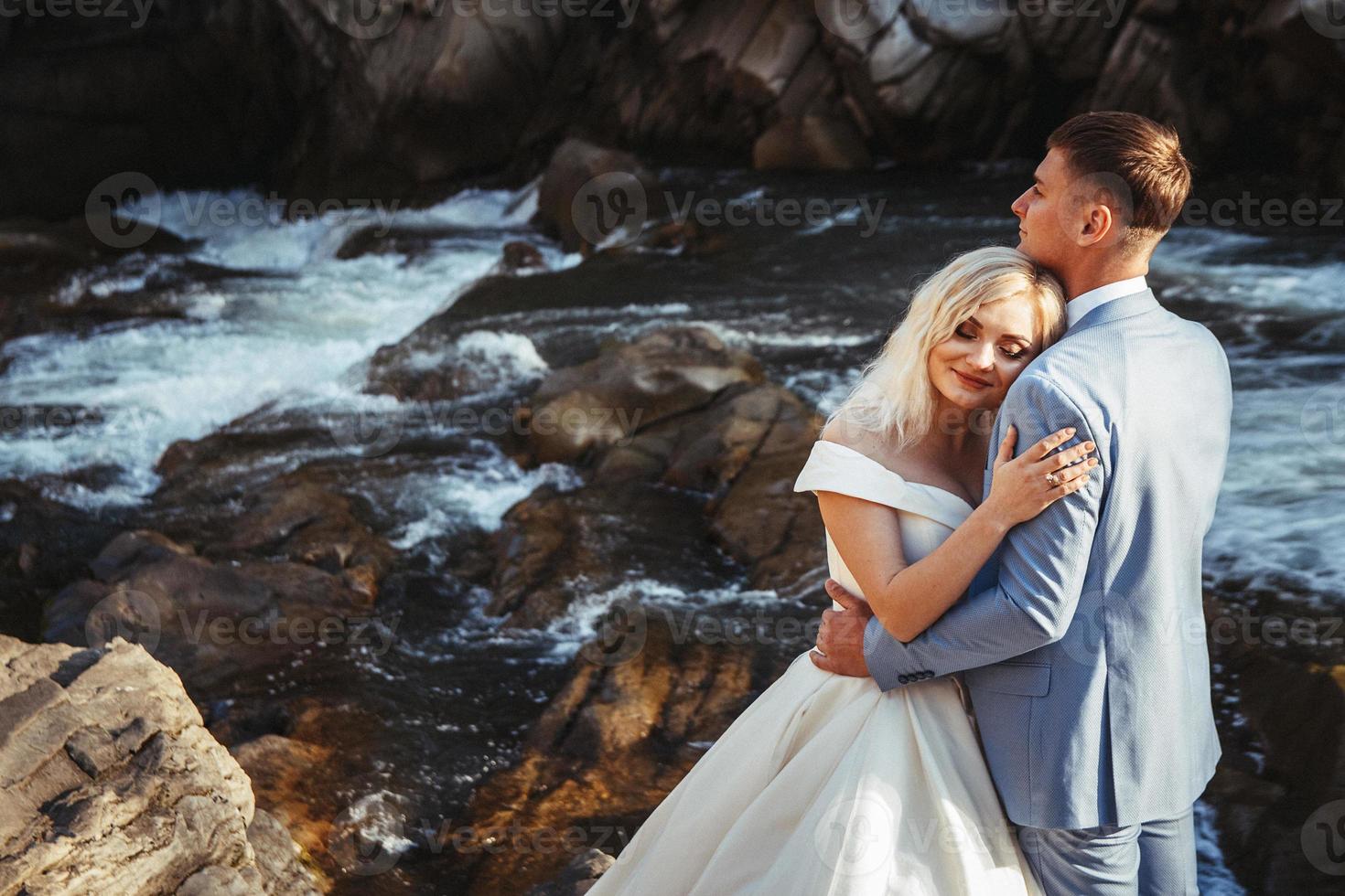 couple marié embrassant avec un fond de montagne et de rivière photo