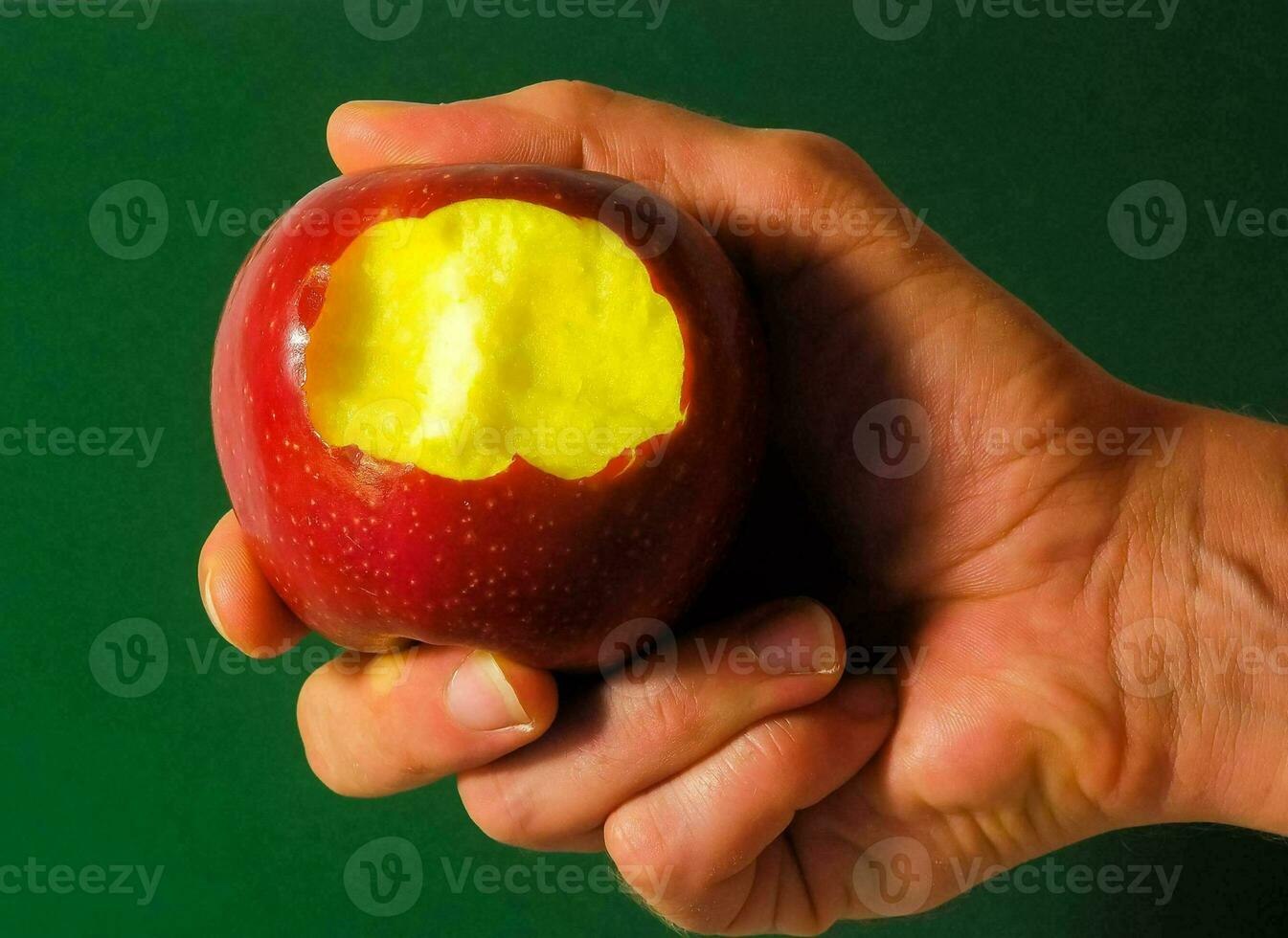 une main en portant un Pomme avec une mordre pris en dehors photo