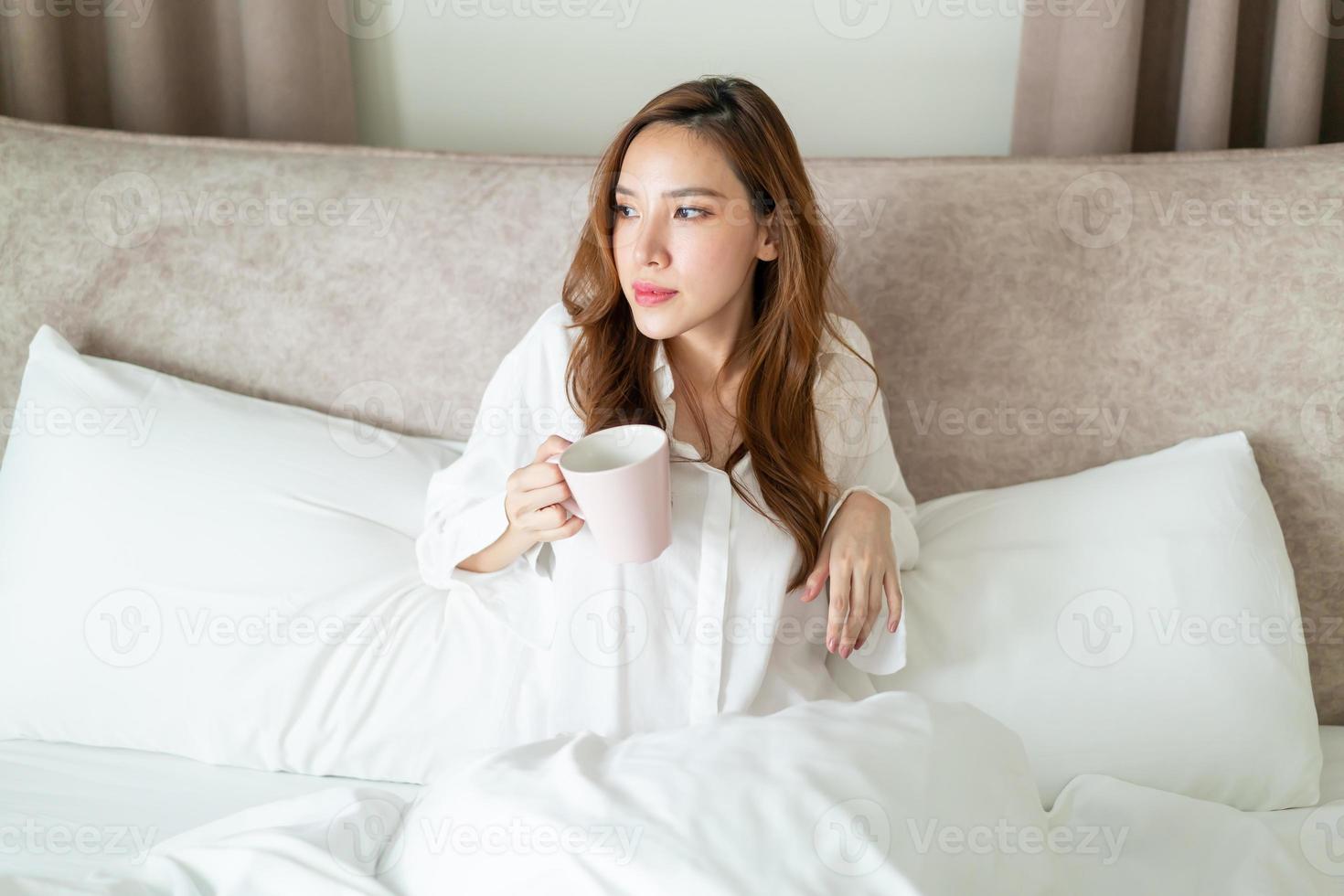 portrait belle femme se réveiller et tenant une tasse de café ou une tasse sur le lit photo