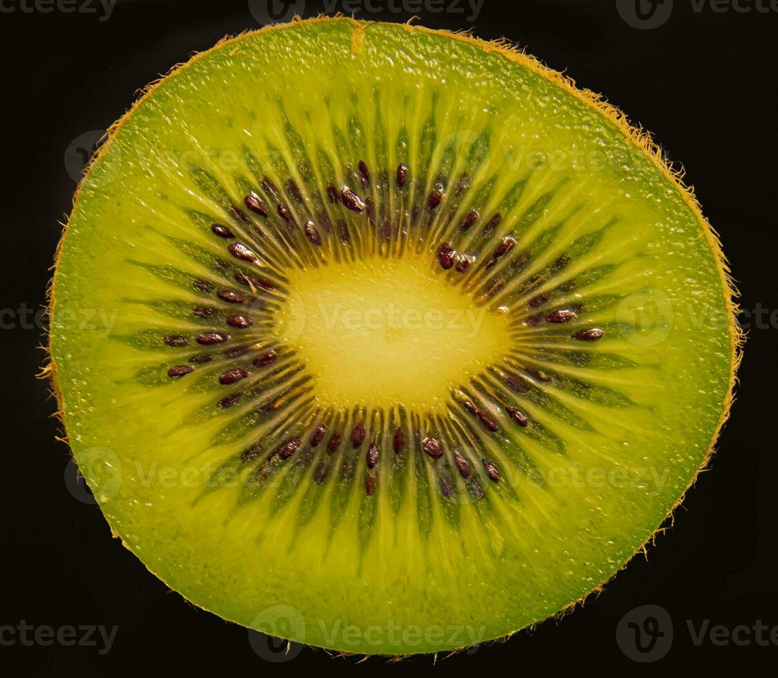 proche en haut de Coupe dans moitié de kiwi fruit tirer contre une noir Contexte. photo