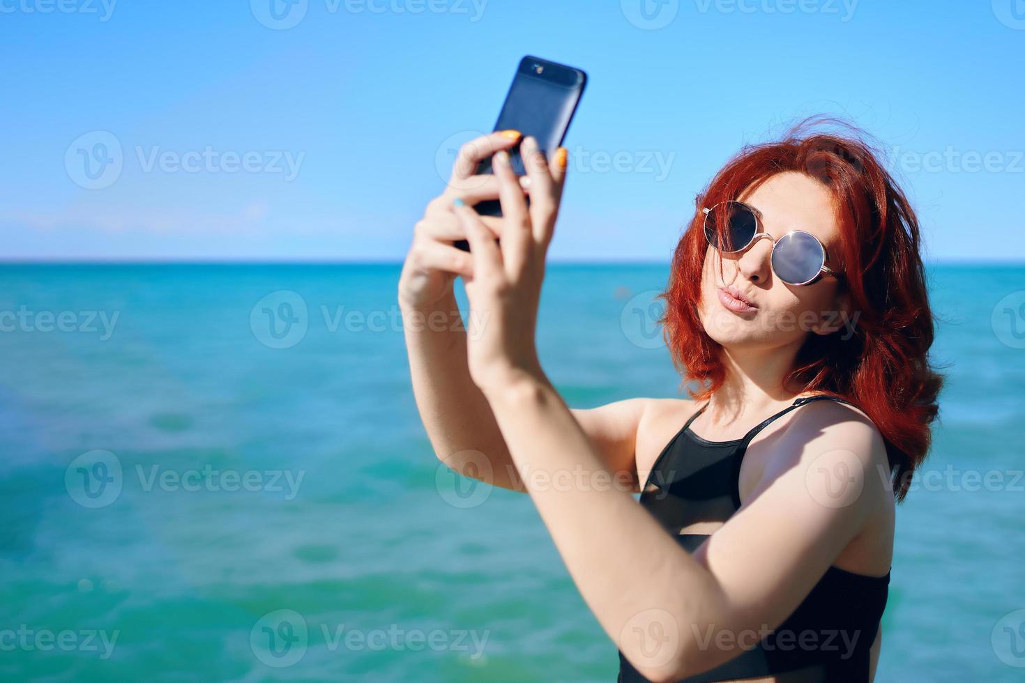 femme rousse prend selfie sur l'appareil photo du smartphone