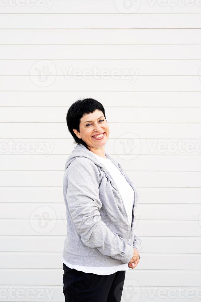 femme portant une veste grise debout à l'extérieur sur fond uni gris photo