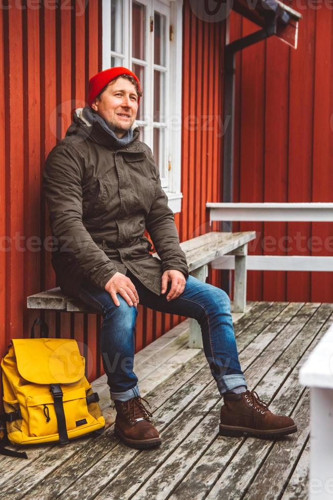 l'homme voyageur est assis près d'une maison en bois de couleur rouge photo