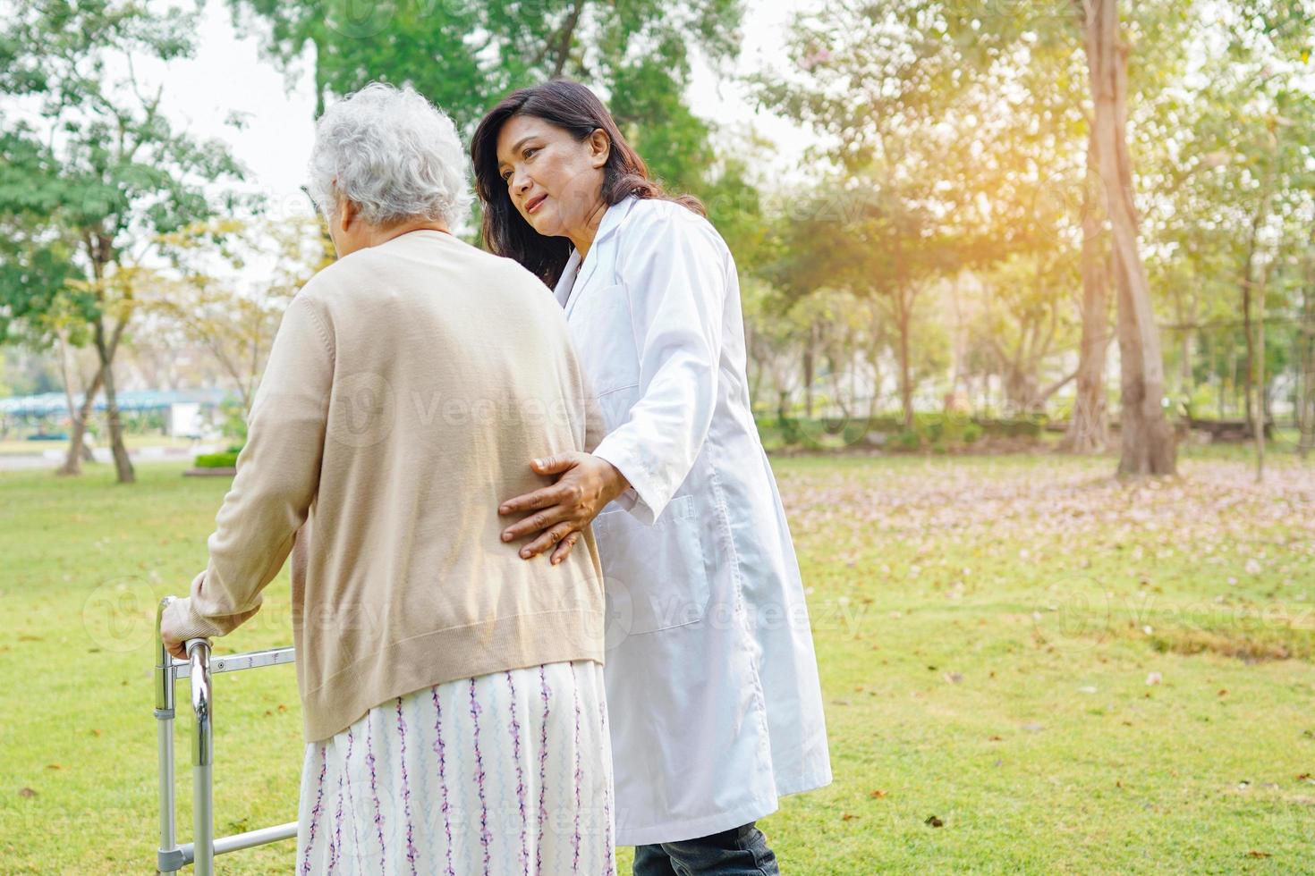 aide d'un médecin et soins une femme âgée asiatique utilise un marcheur dans le parc. photo