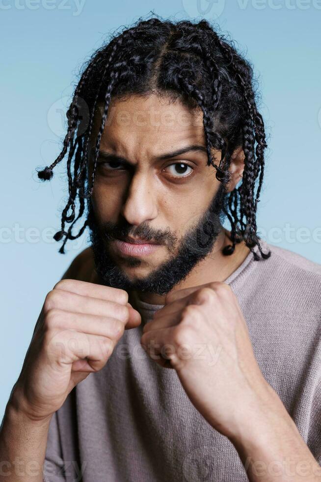 sérieux arabe homme boxeur à la recherche à caméra avec serré les poings dans combat position. sur de soi la personne montrant force tandis que permanent dans boxe pose prêt à attaque portrait photo