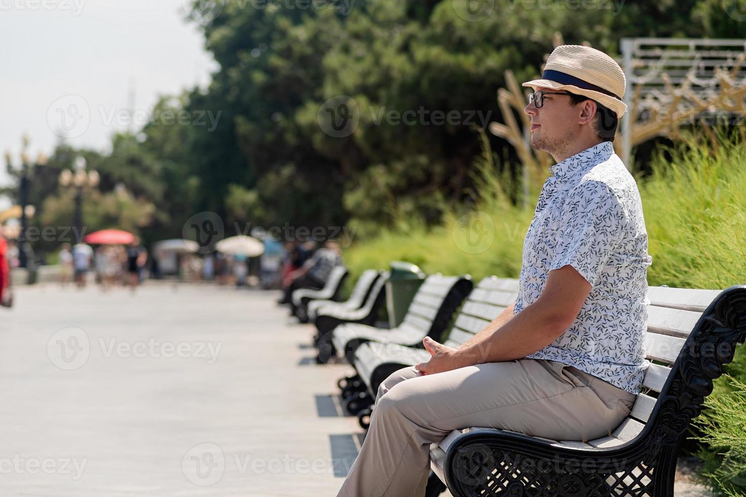 homme assis sur le banc sur le remblai de la mer, se reposer photo