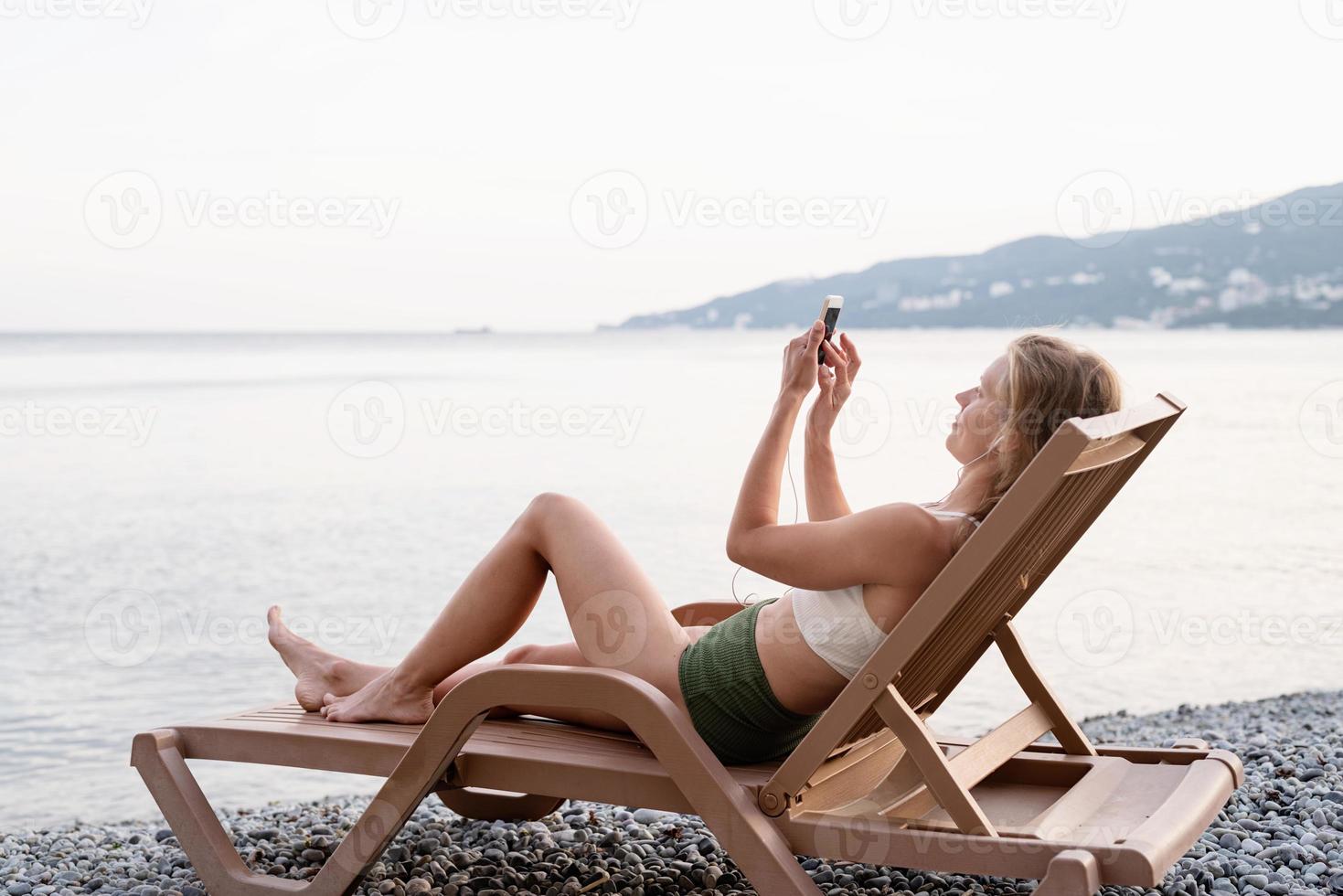 jeune femme allongée sur la chaise longue écoutant de la musique photo
