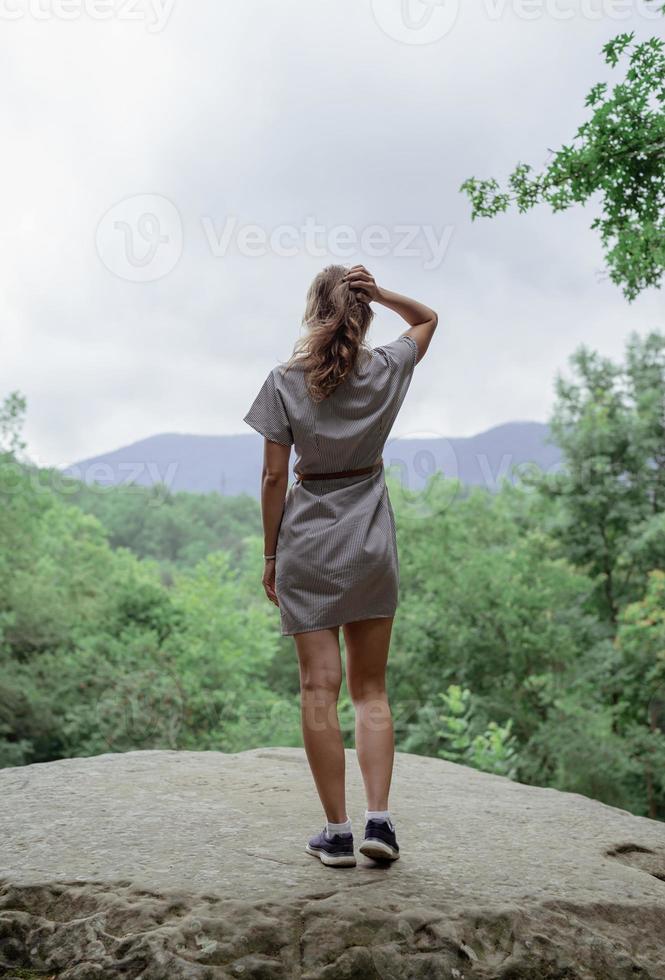 Jeune femme debout sur un gros rocher dans la forêt à l'écart photo