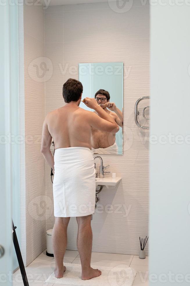 un jeune homme se brosse les dents dans la salle de bain photo