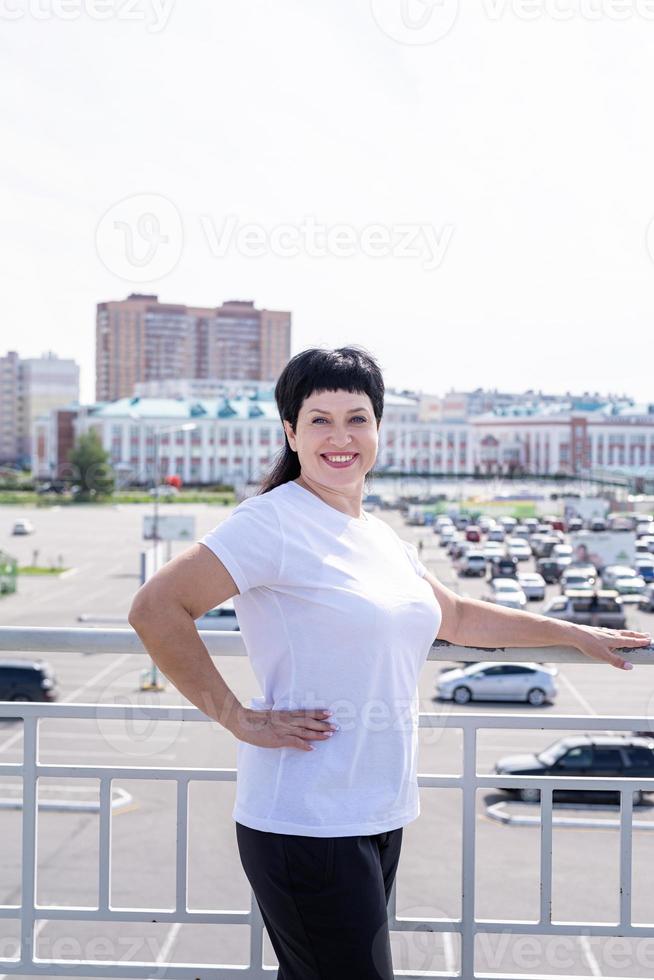 femme âgée souriante travaillant à l'extérieur sur fond urbain photo