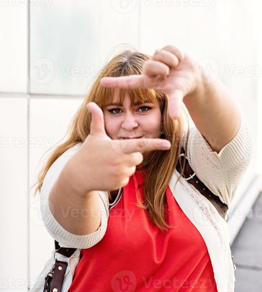 jolie femme en surpoids faisant le cadre avec les mains. photo