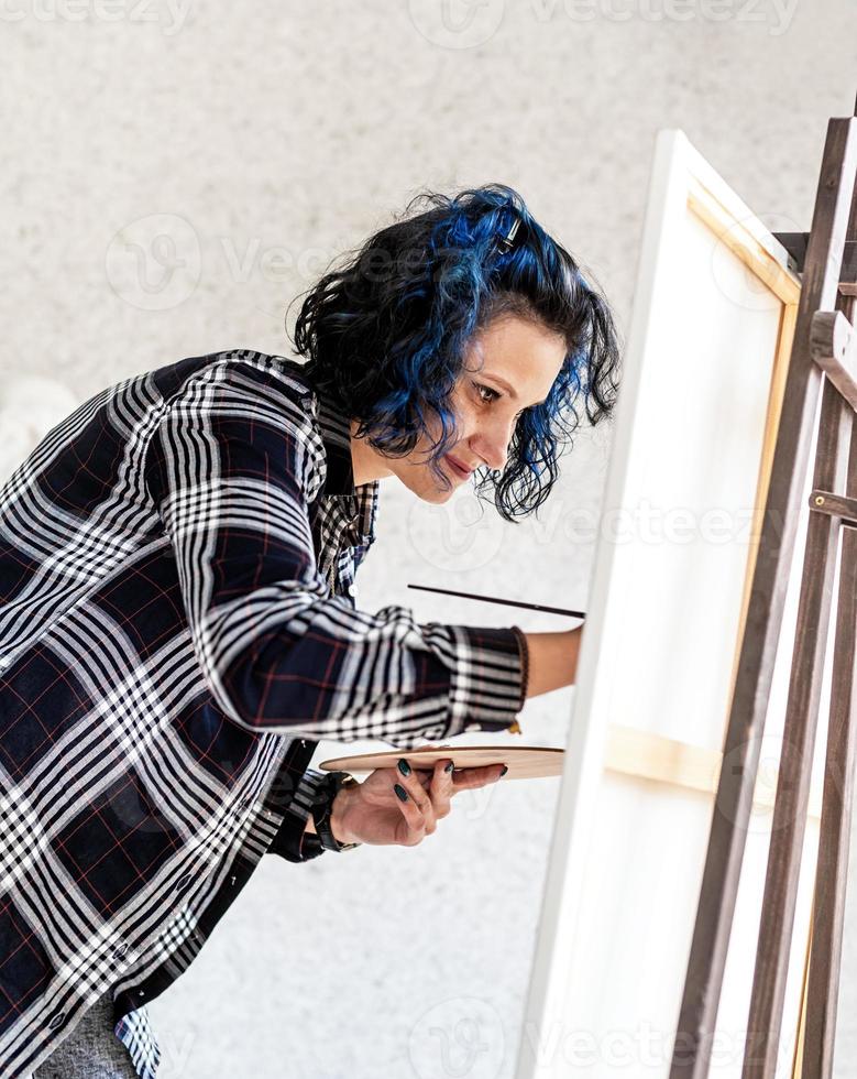 femme créative avec la peinture de cheveux teints en bleu dans son studio photo