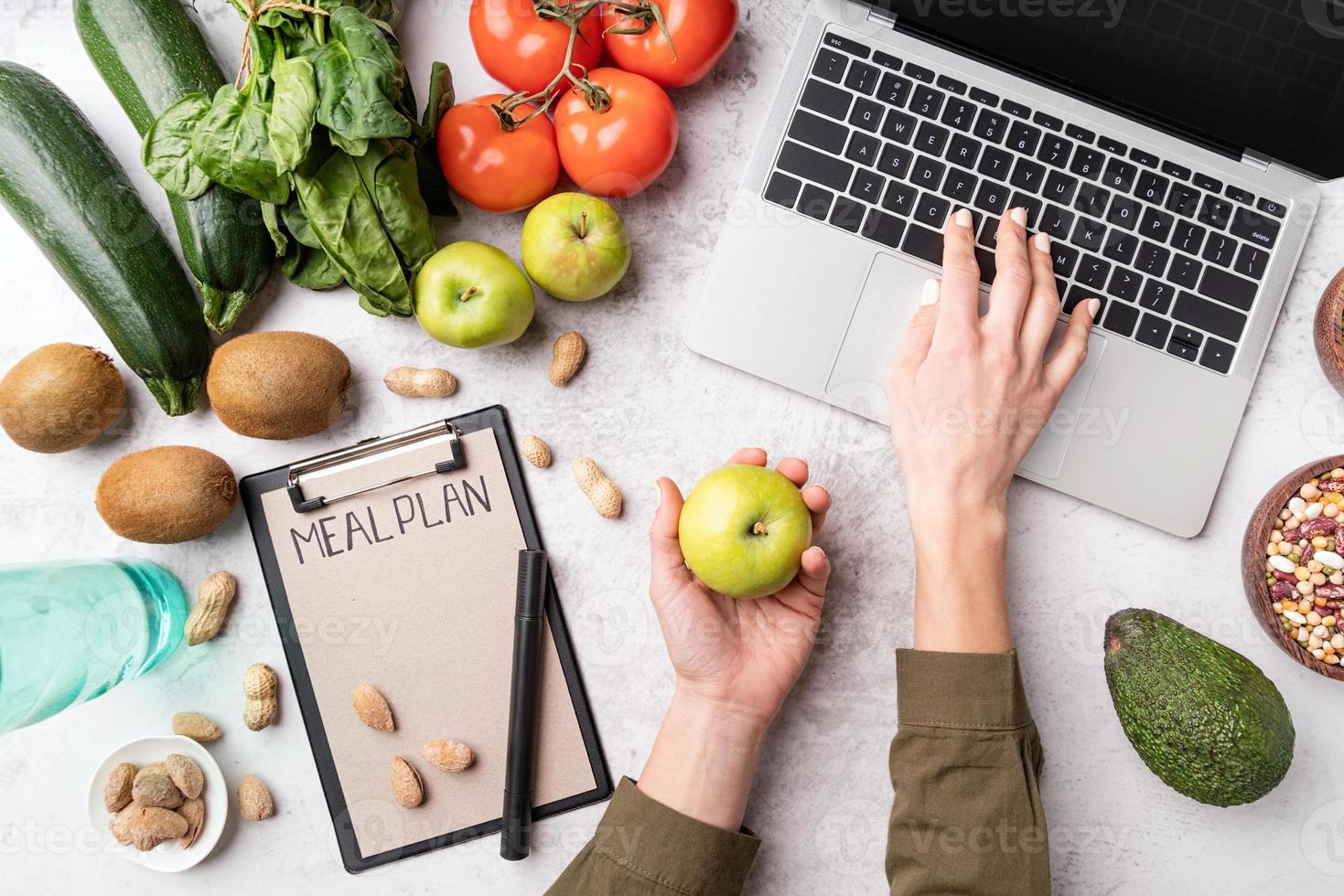 Les mains des femmes écrivant dans le bloc-notes mots plan de repas vue de dessus mise à plat photo