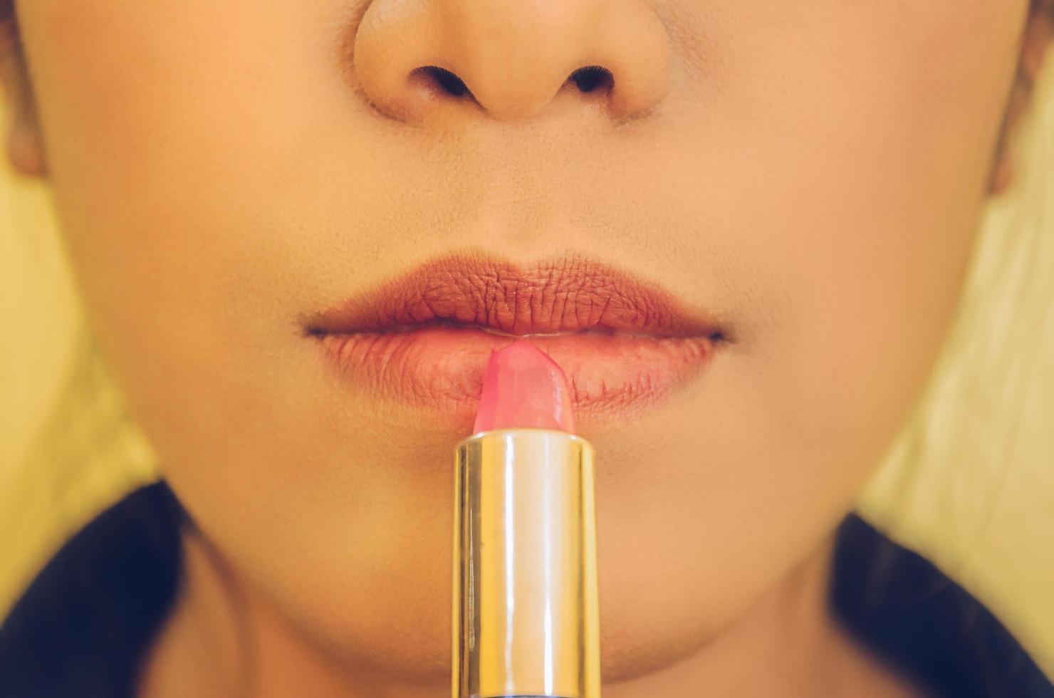 visage de beauté de la femme en appliquant du rouge à lèvres sur la bouche par des cosmétiques. photo