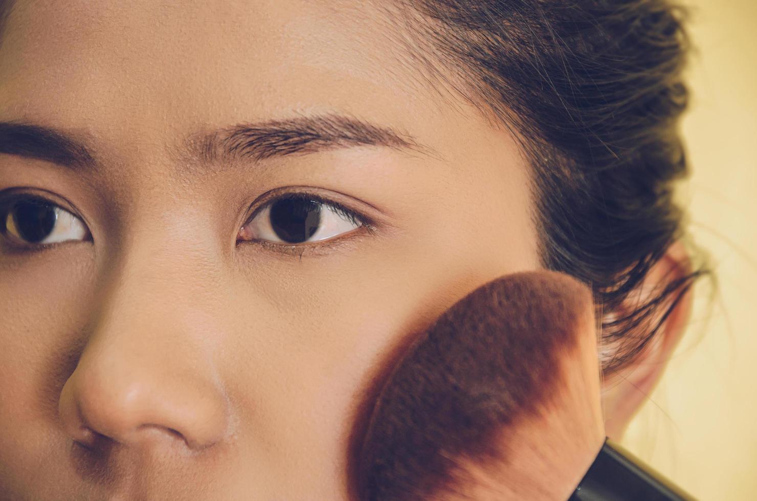 visage de beauté d'une femme asiatique en appliquant des pinceaux sur la peau par des cosmétiques. photo