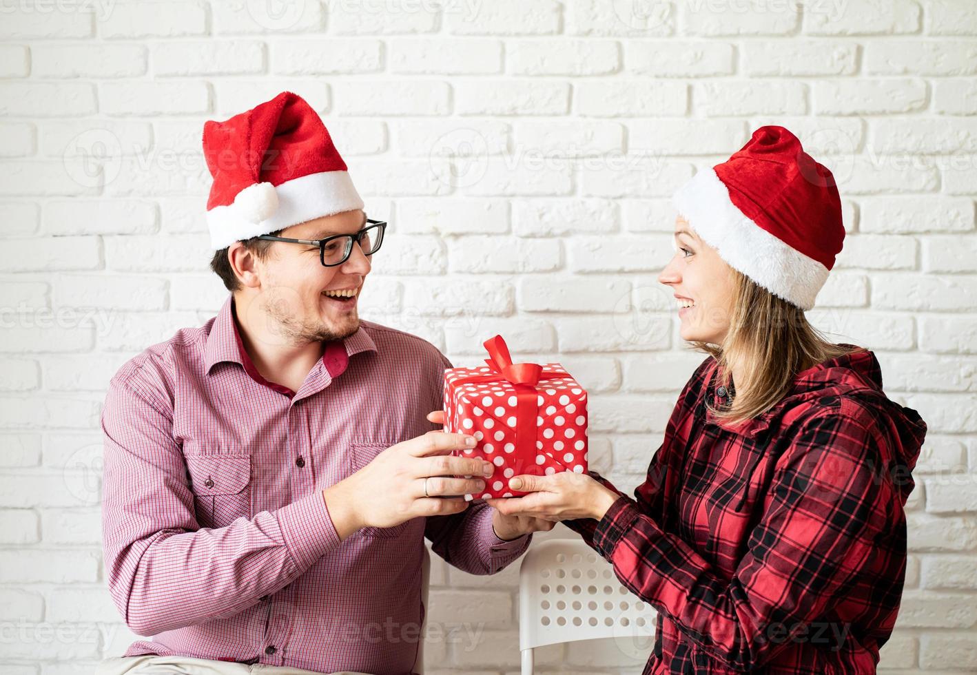 Couple in santa hats célébrant les vacances sur fond de briques blanches photo