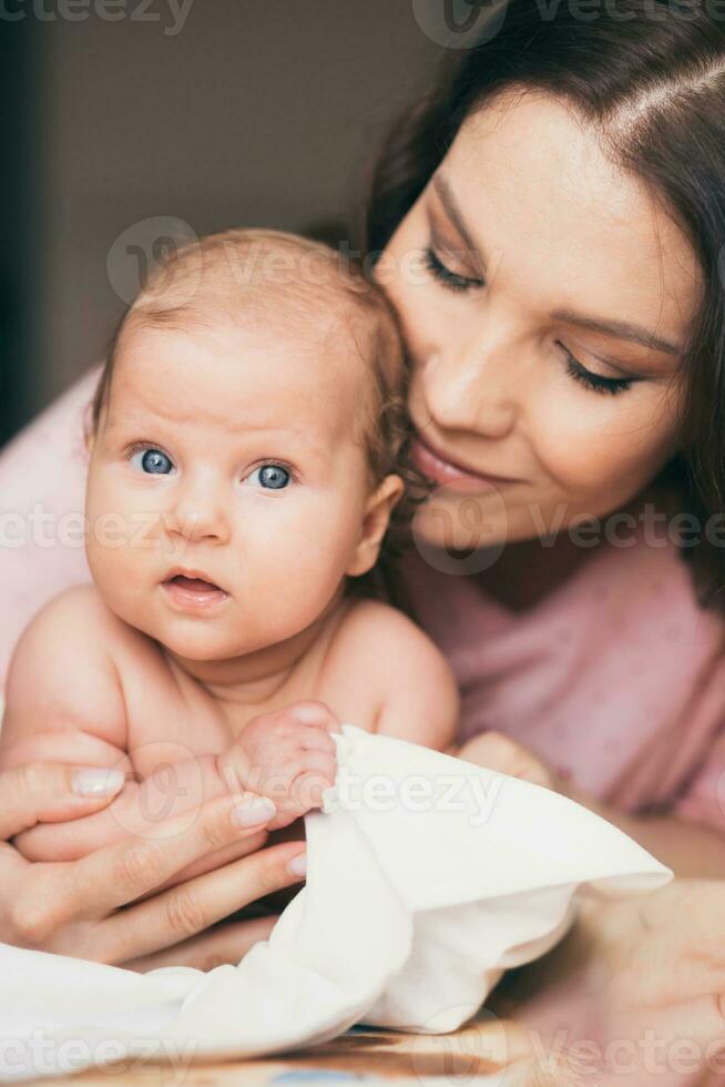 portrait de une Jeune femme qui tendrement se soucie pour sa bébé photo