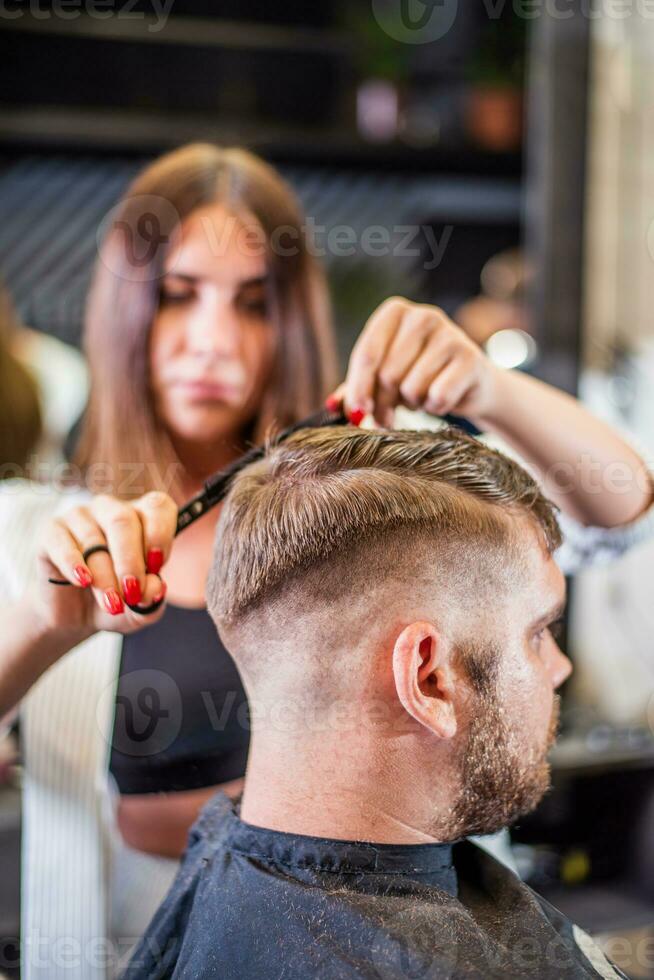 coiffeur Coupe avec les ciseaux barbu homme dans salon de coiffure photo