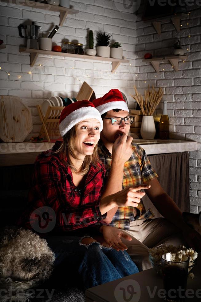 couple regardant des films à la maison à Noël pointant vers l'écran photo