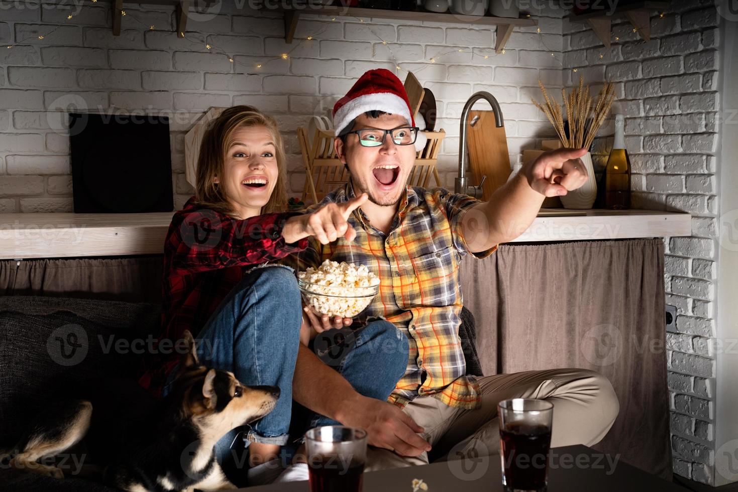 couple regardant des films à la maison à Noël pointant vers l'écran photo