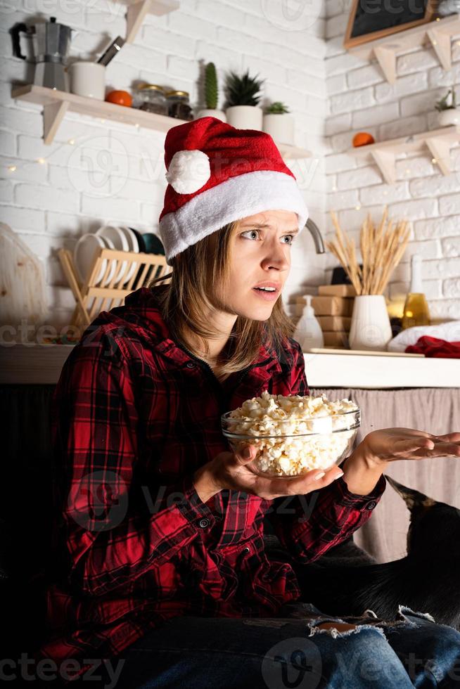 Woman in santa hat regarder des films à la maison la nuit de Noël photo