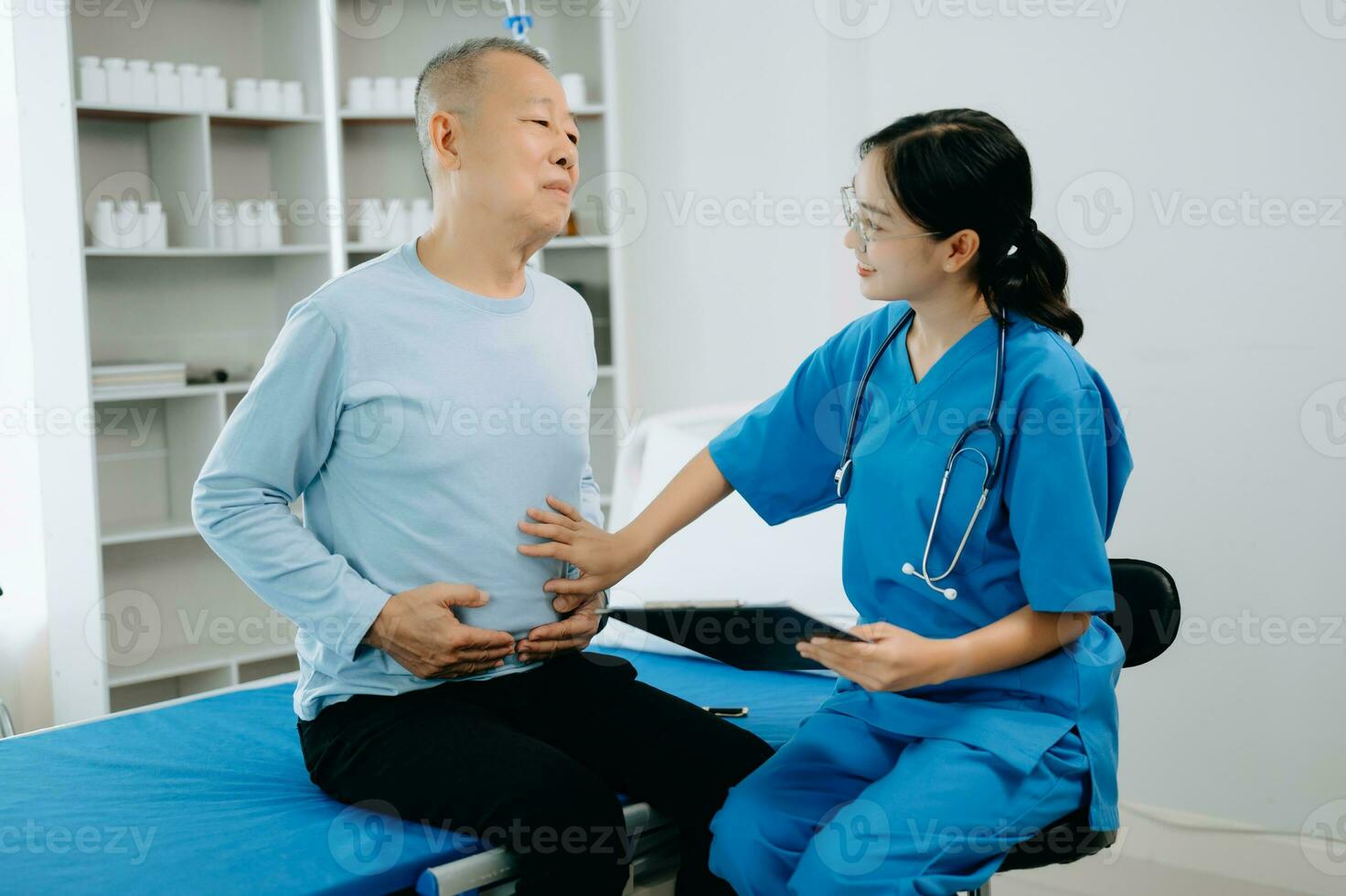 asiatique médecin dans blanc costume prendre Remarques tandis que discuter et asiatique âgé, homme patient qui mensonge sur lit avec recevoir saline Solution dans hôpital ou clinique. photo