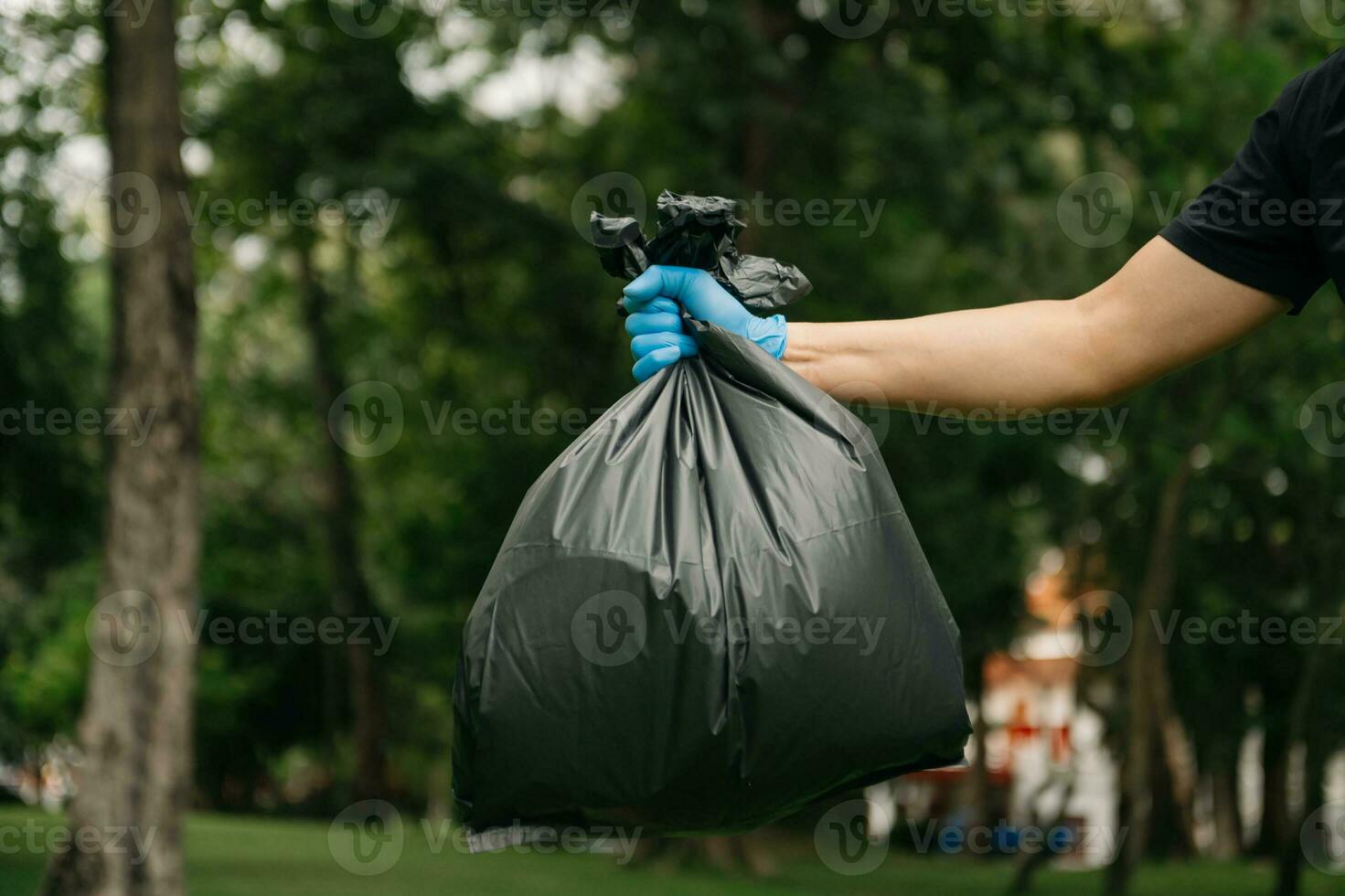 main en portant des ordures noir sac en mettant dans à poubelle à faire le ménage. clairière, pollution, écologie et Plastique concept. photo