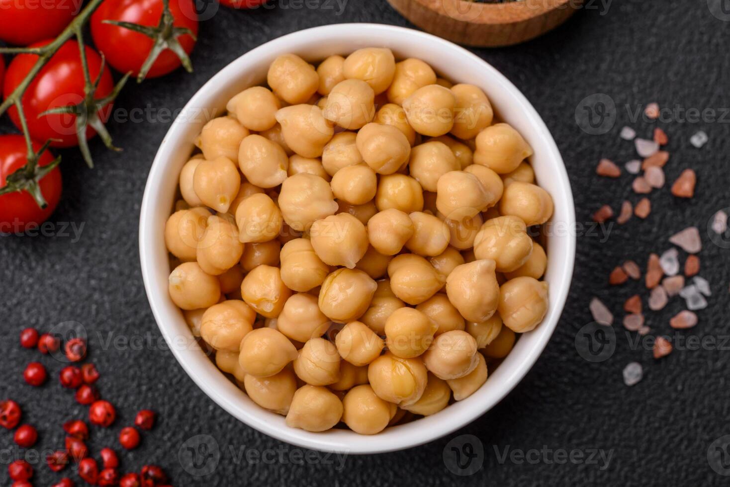 délicieux en conserve pois chiches dans une céramique assiette sur une foncé béton Contexte photo