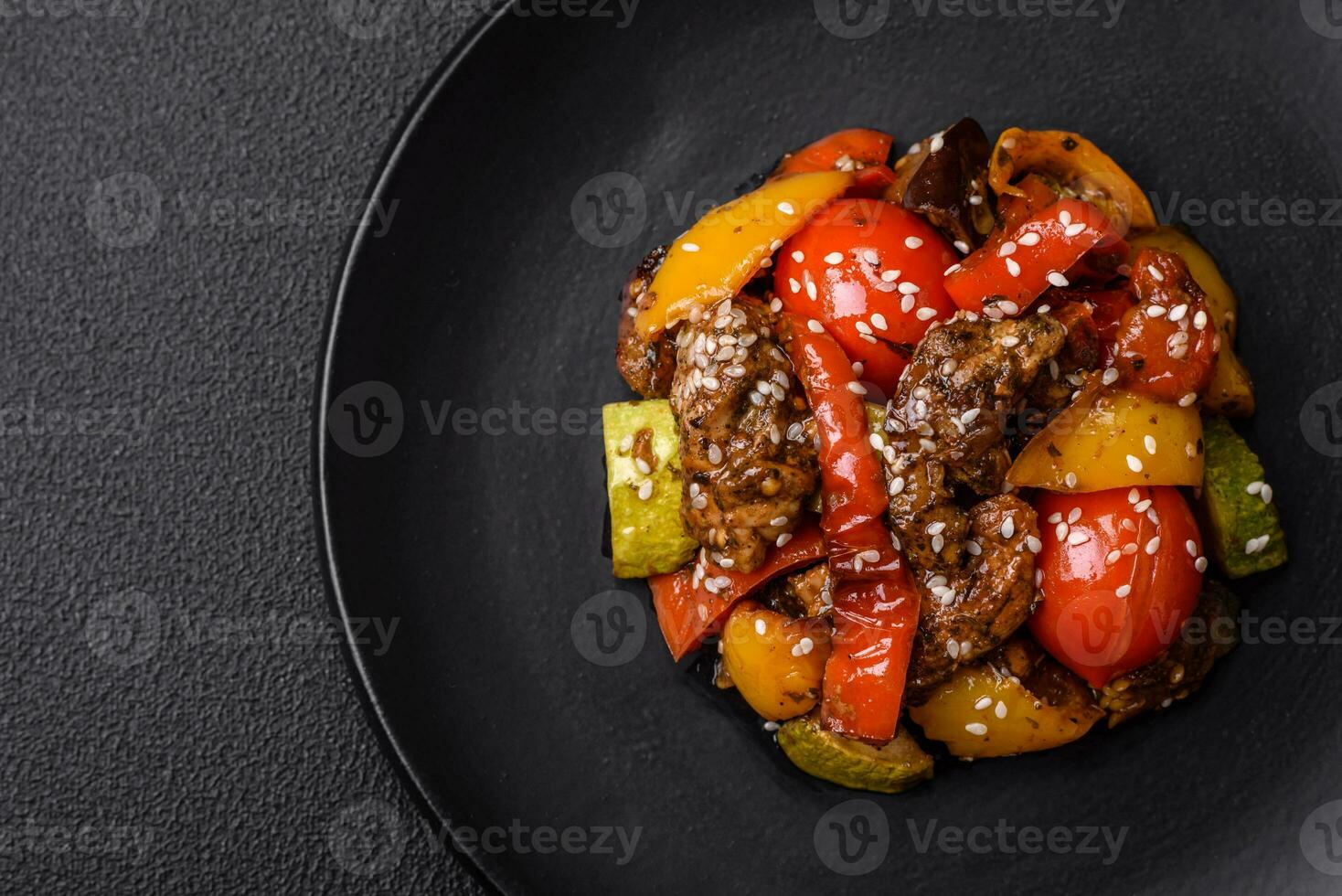 chaud salade avec veau, tomates, poivrons, courgette, sésame, sel, épices et herbes photo