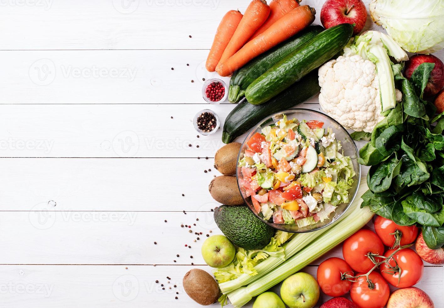 saladier, fruits et légumes sur fond de bois blanc photo