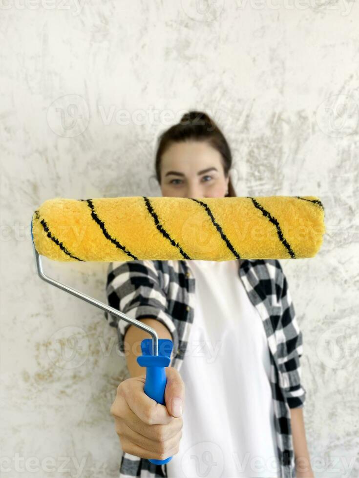 brunette fille avec peindre rouleau. fille Faire rénovations dans le appartement. photo