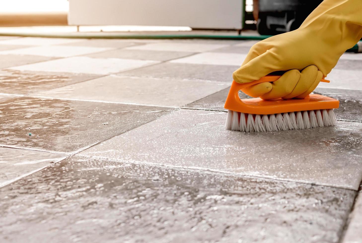 à l'aide d'une brosse à plancher en plastique pour frotter le sol carrelé. photo