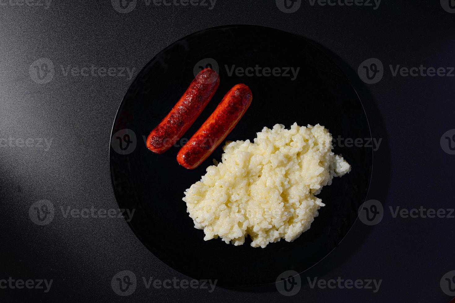 saucisses grillées avec du riz sur une plaque noire avec fond noir photo