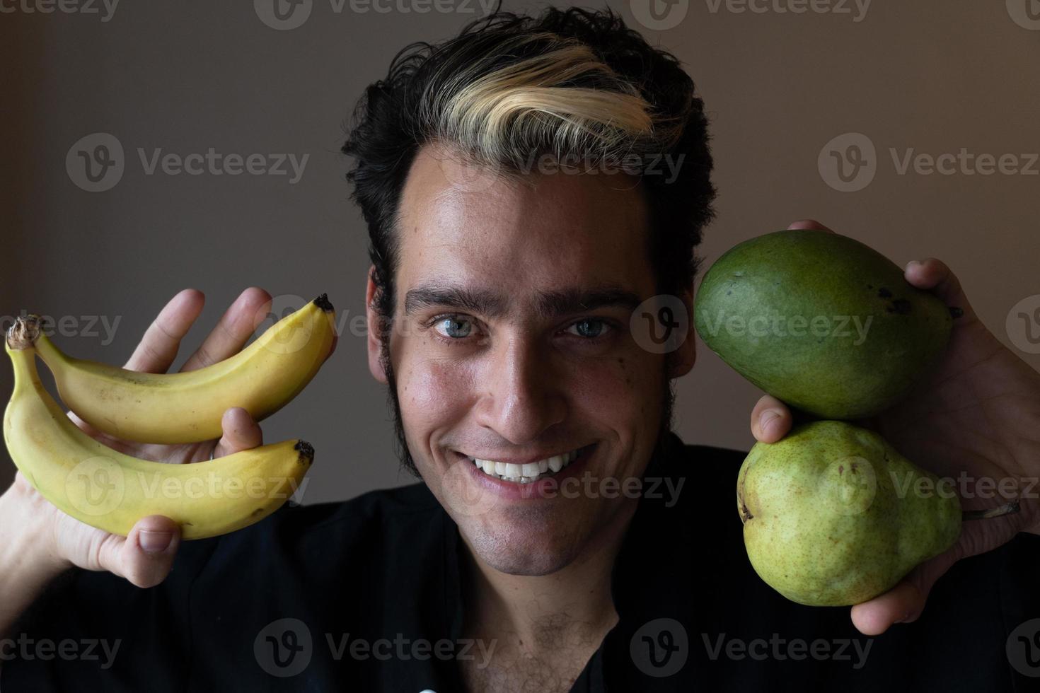 l'homme sourit et tient des fruits à proximité. favorise les aliments crus sains photo