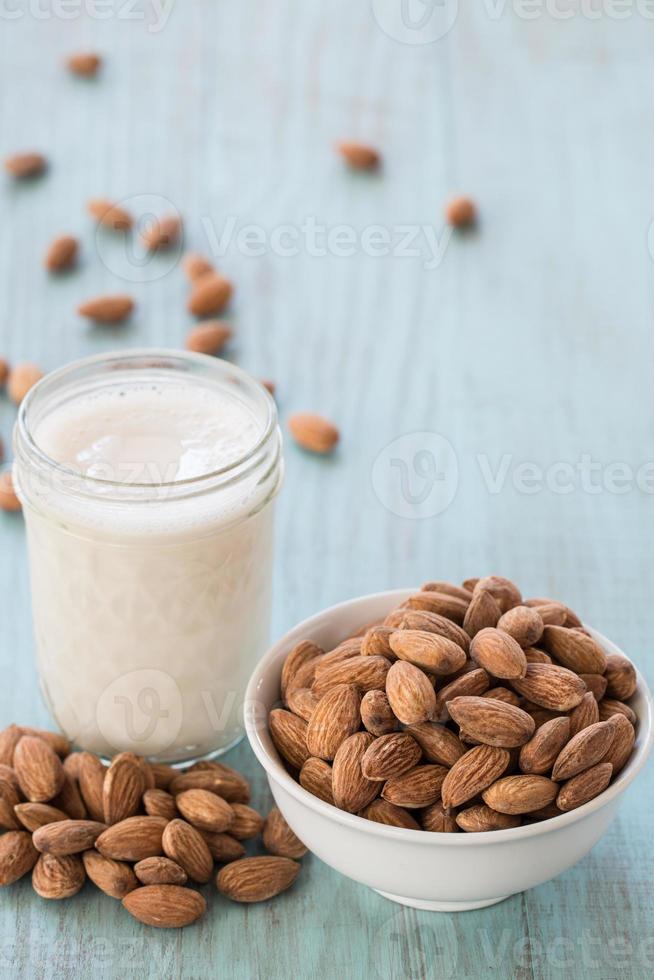 amandes dans un bol blanc avec un verre de lait fond bleu photo