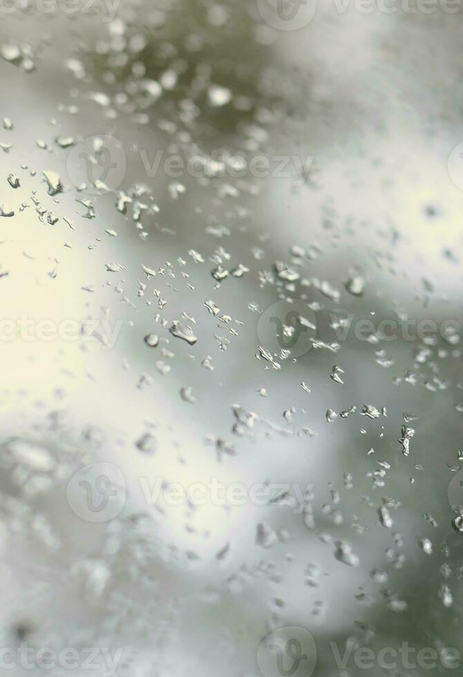 une photo de gouttes de pluie sur la vitre avec une vue floue des arbres verts en fleurs. image abstraite montrant des conditions météorologiques nuageuses et pluvieuses