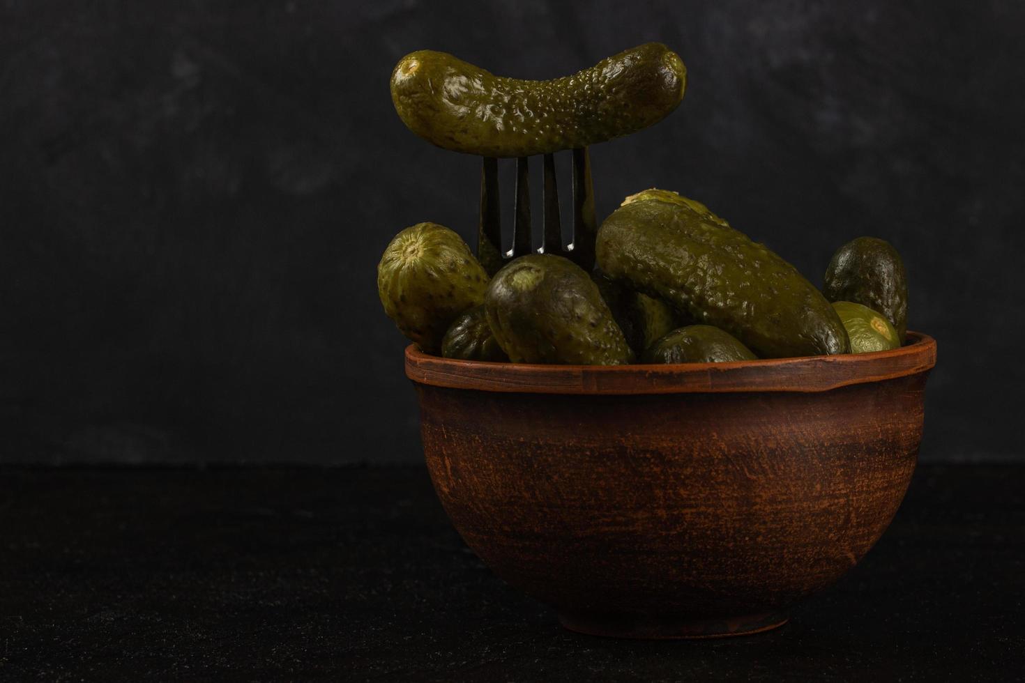 cornichons et choucroute dans un bol en argile sur fond de béton foncé photo