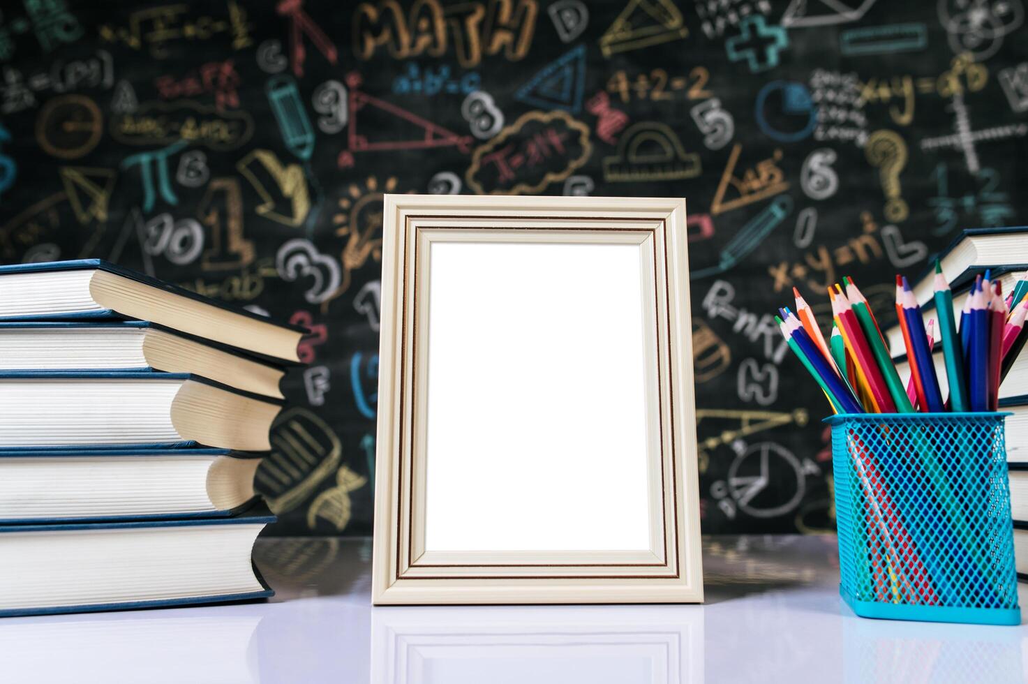 cadre photo blanc, livre et crayons de couleur en classe