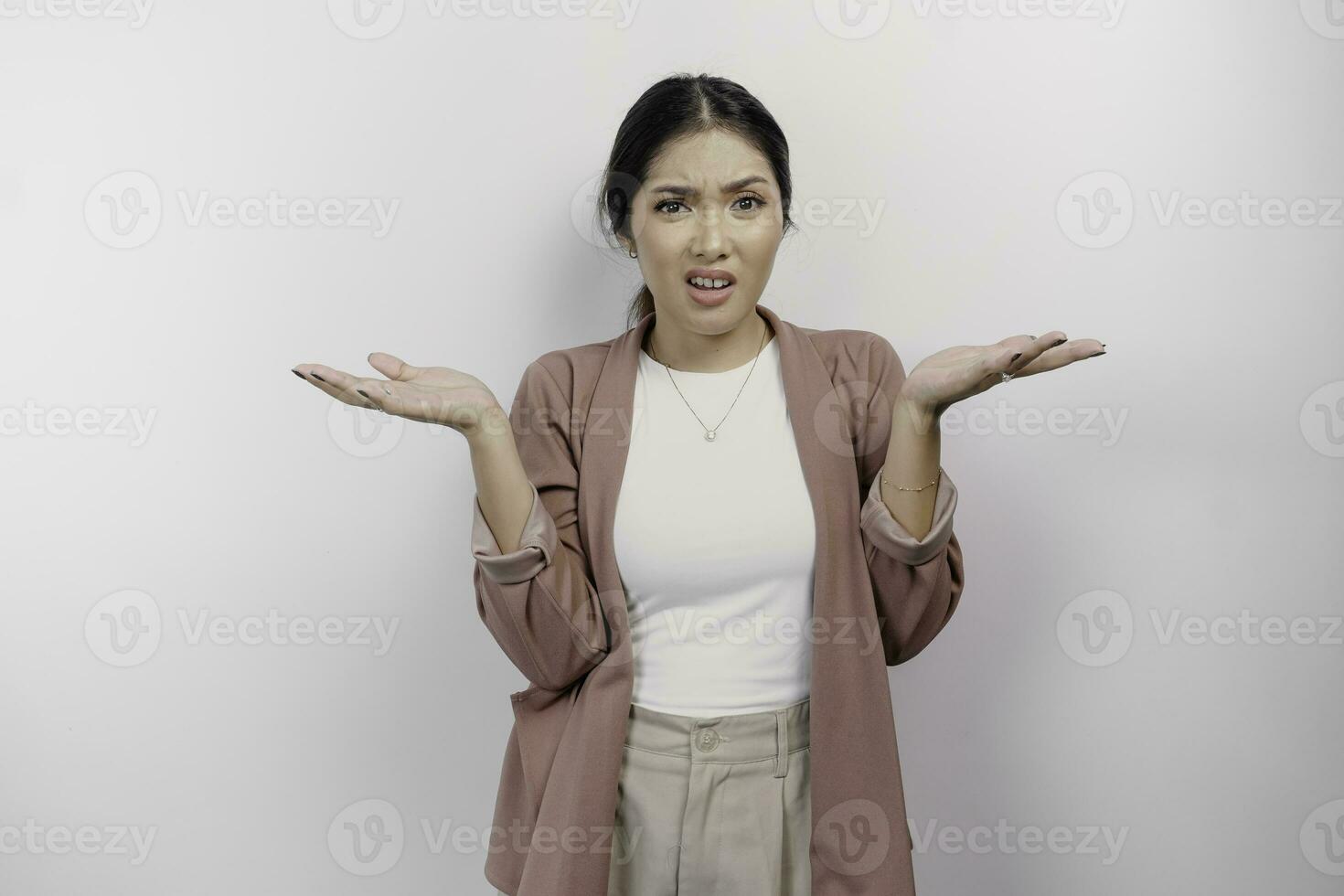 un asiatique femme employé portant une cardigan regards donc confus entre les choix, isolé par une blanc Contexte photo