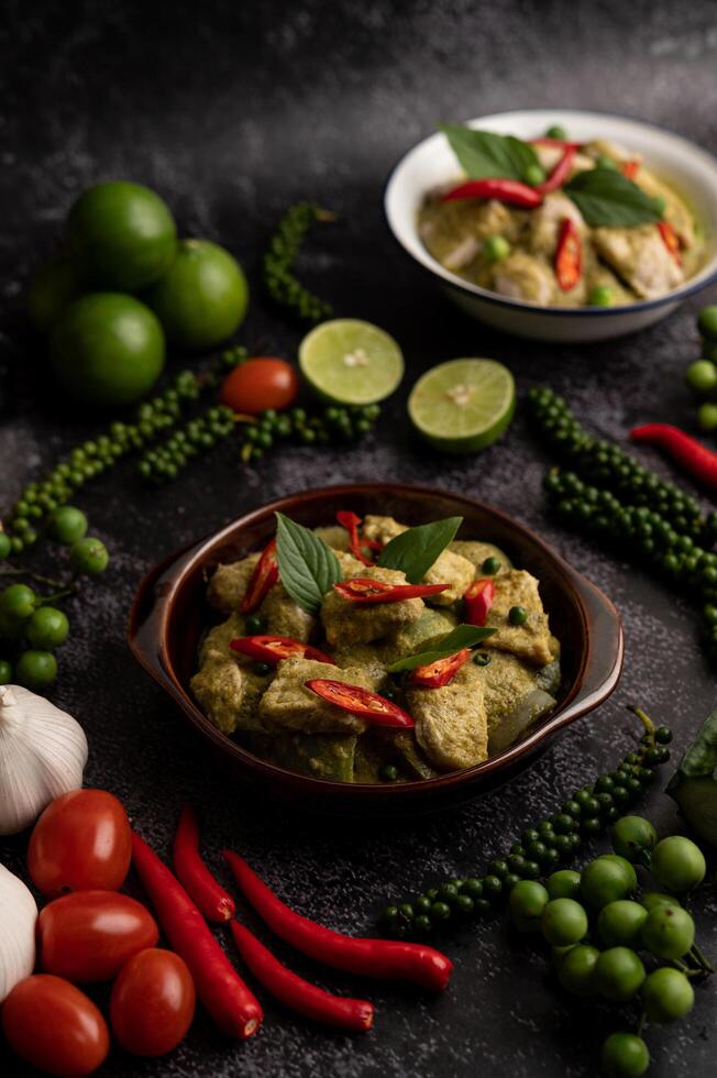 curry vert de porc dans un bol marron avec des épices sur un ciment noir photo