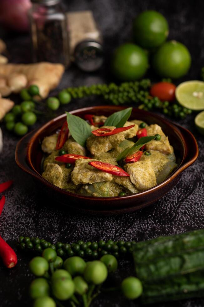 curry vert de porc dans un bol marron avec des épices sur un ciment noir photo