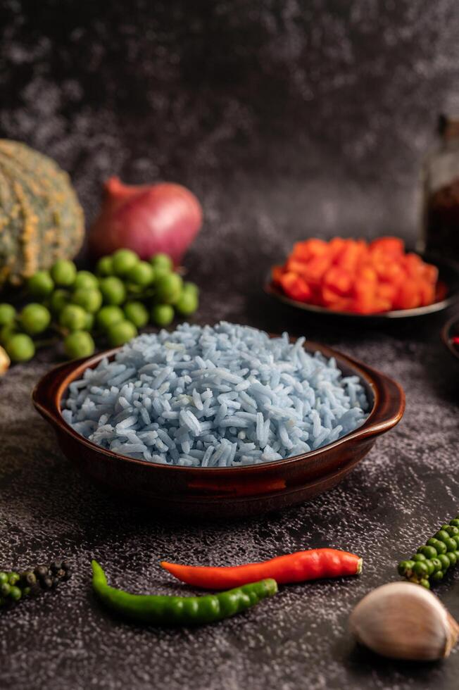 riz aux fleurs de pois papillon dans une tasse brune aux épices sur ciment noir. photo