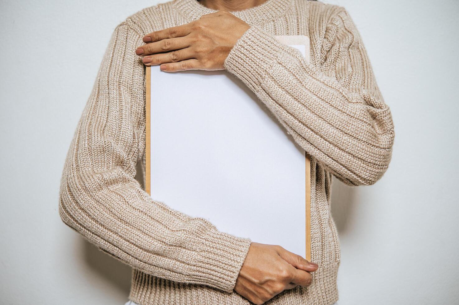 un peuple à manches longues tient un presse-papiers sur sa poitrine. photo