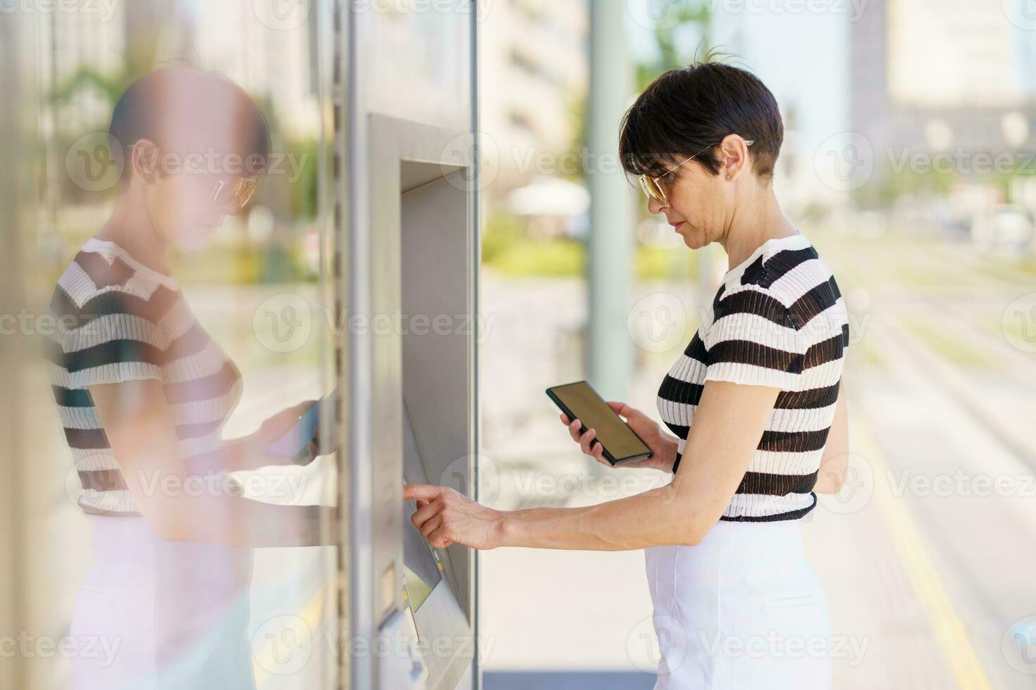 concentré femme en utilisant téléphone intelligent et Terminal sur rue photo