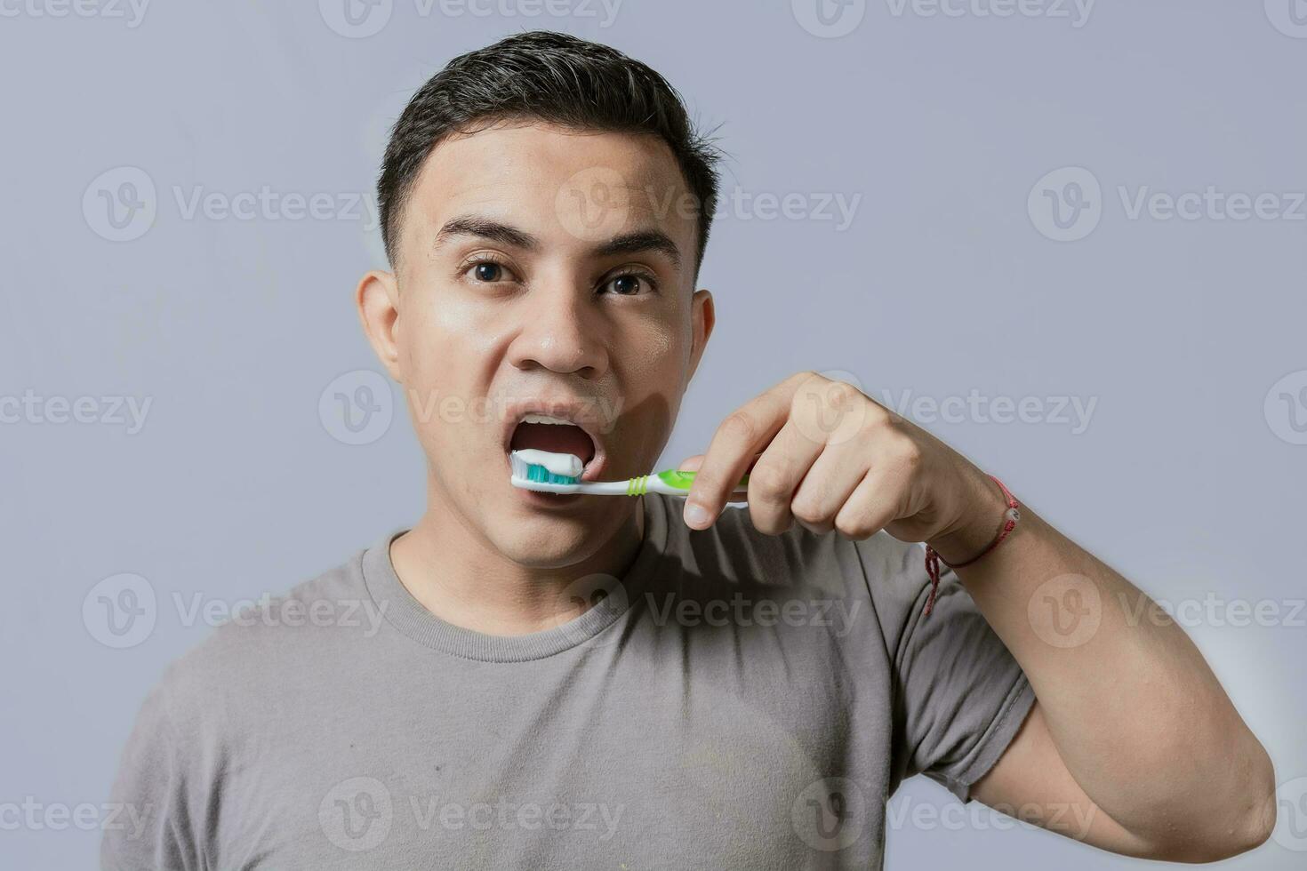 Beau gars brossage le sien les dents isolé, proche en haut de Beau homme brossage le sien dents. brossage et dentaire hygiène concept. proche en haut de gens brossage leur les dents sur isolé Contexte photo