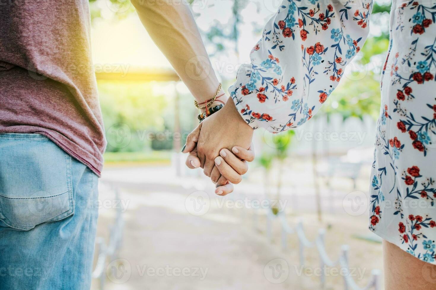 proche en haut de couple en portant mains en plein air, proche en haut de Jeune couple en marchant en portant mains. fermer de adolescents en portant mains dans une parc. vue de Jeune couple en portant mains en plein air photo