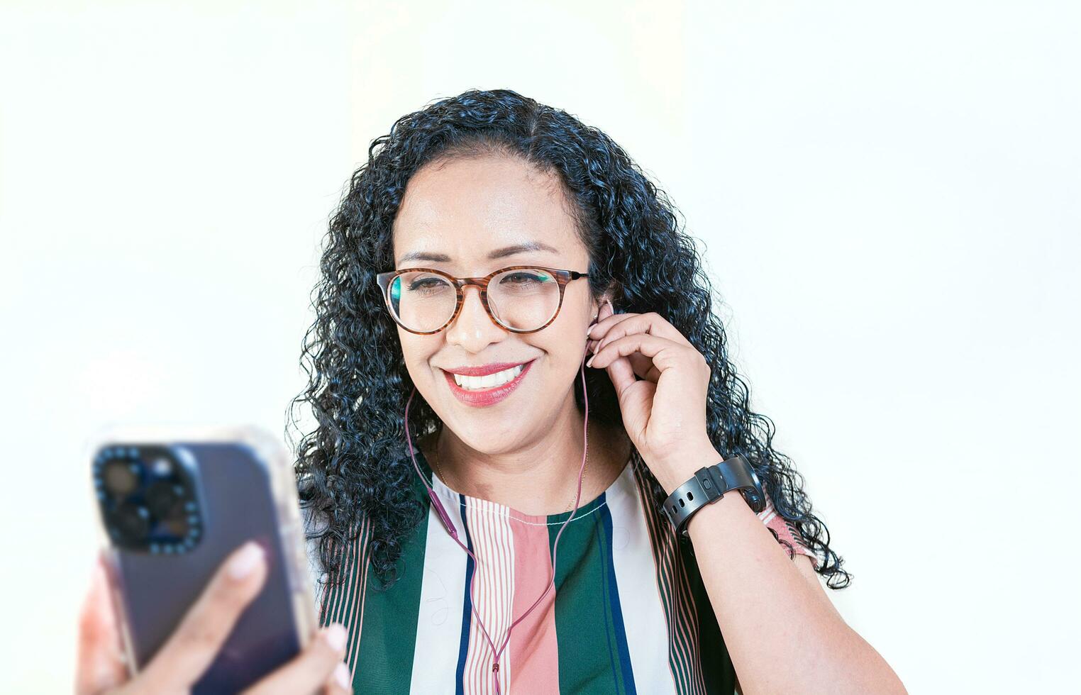 proche en haut de de bonne humeur afro fille écoute Chansons avec téléphone portable sur isolé Contexte. Jeune afro femme écoute à la musique avec écouteurs isolé photo