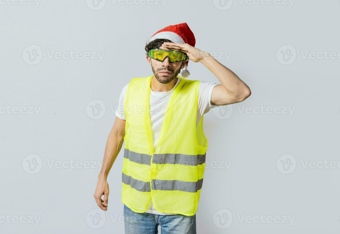 ingénieur dans Noël chapeau à la recherche à quelque chose dans le distance. ingénieur dans une gilet et Noël chapeau à la recherche dans le distance. constructeur homme dans une gilet et Noël chapeau à la recherche dans le distance photo